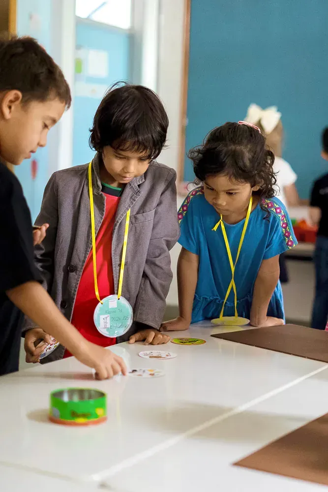 A group of children are standing around a table in a classroom.