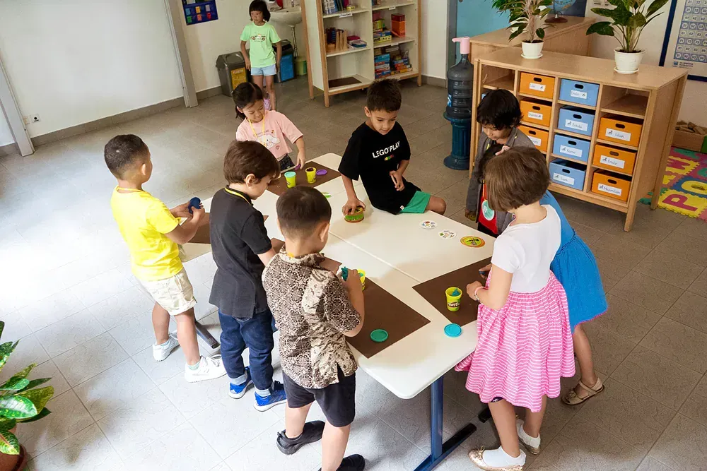 A group of children are sitting around a table in a classroom.