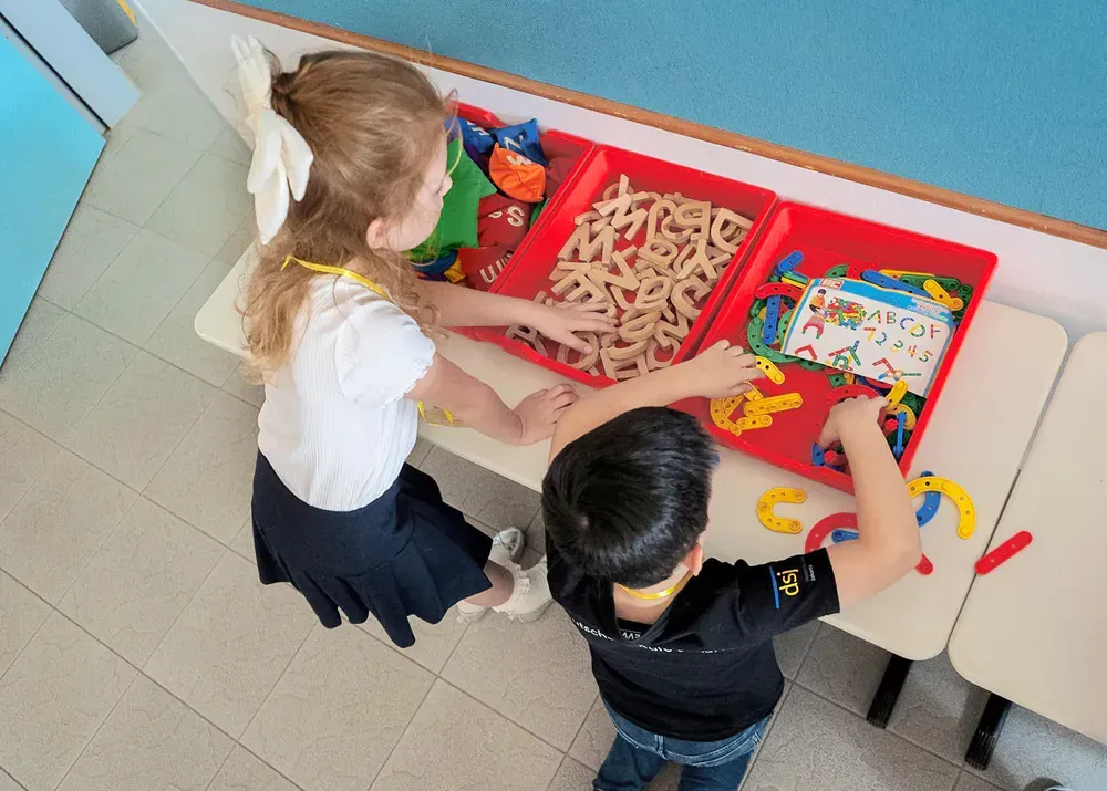 A boy and a girl are playing with toys on a table.