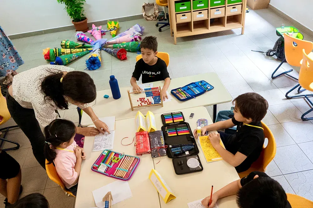 A group of children are sitting around a table in a classroom.