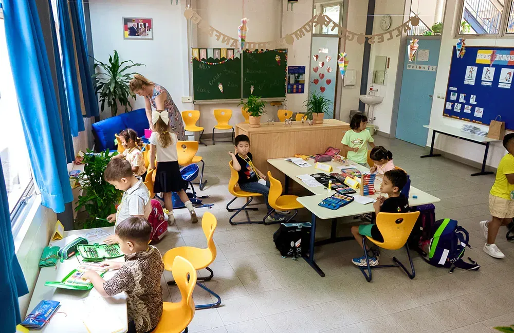 A group of children are sitting at tables in a classroom.
