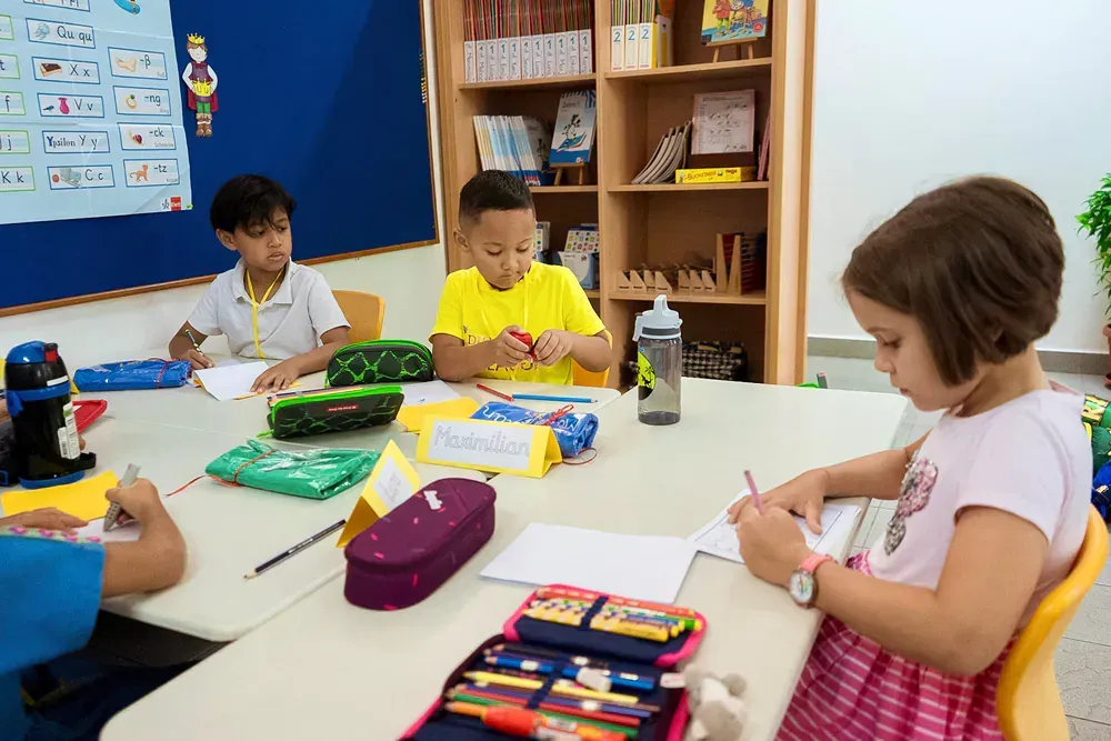 A group of children are sitting around a table in a classroom.