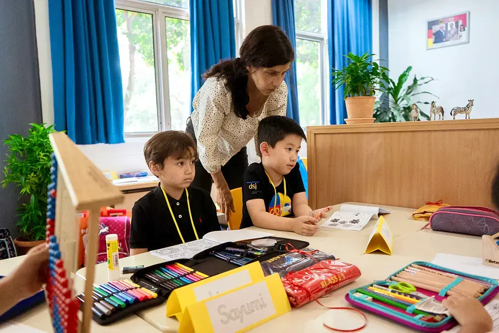 A woman is teaching two young boys in a classroom.