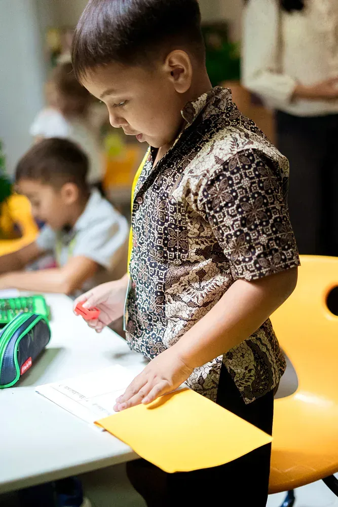 A young boy is cutting a piece of paper with scissors.