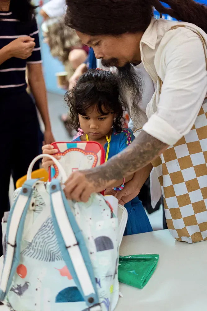 A man and a little girl are looking into a backpack.
