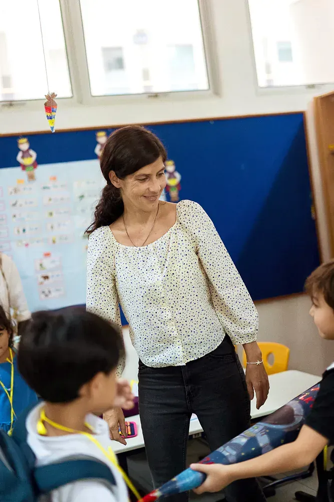 A woman is talking to a group of children in a classroom.