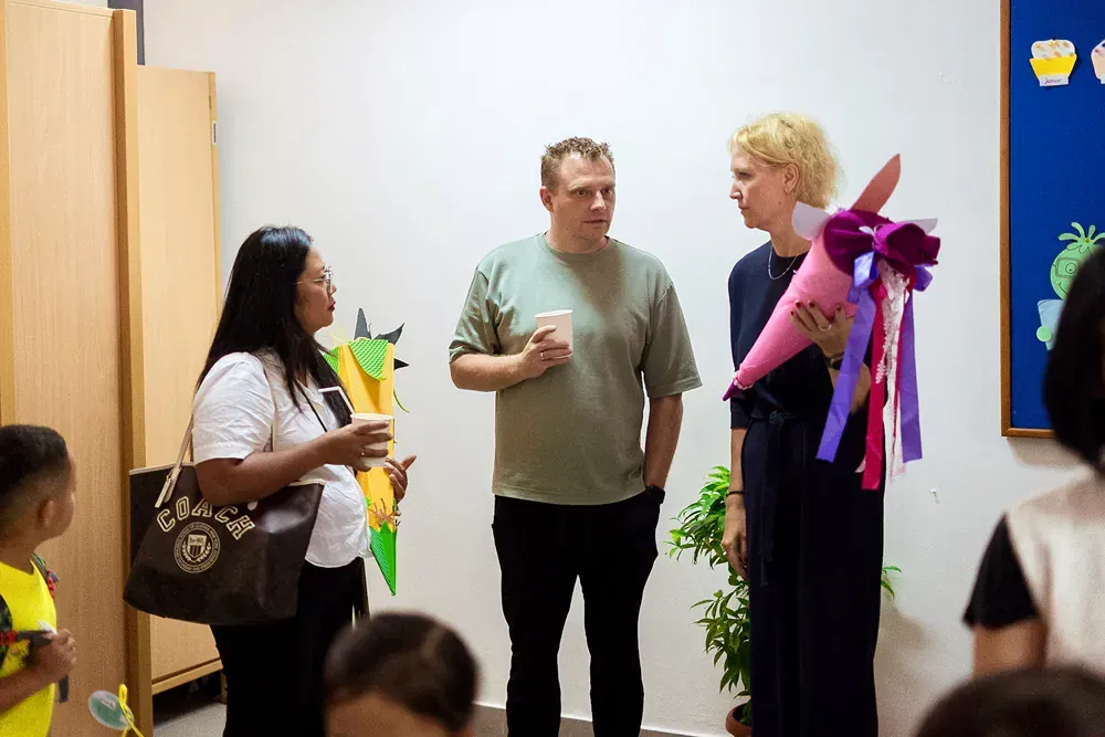 A group of people are standing in a room talking to each other.