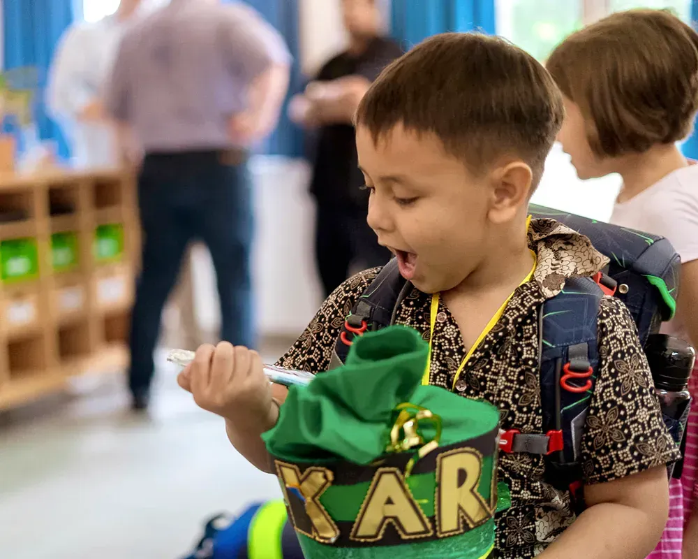 A young boy is holding a green bag that says kar on it