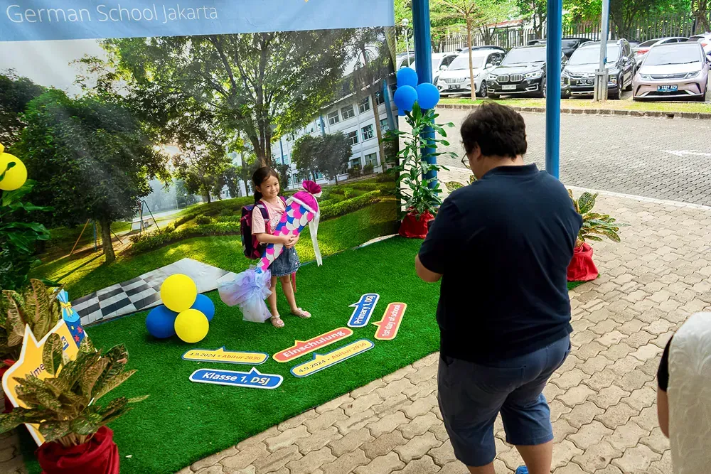 A man is taking a picture of a little girl holding a kite.