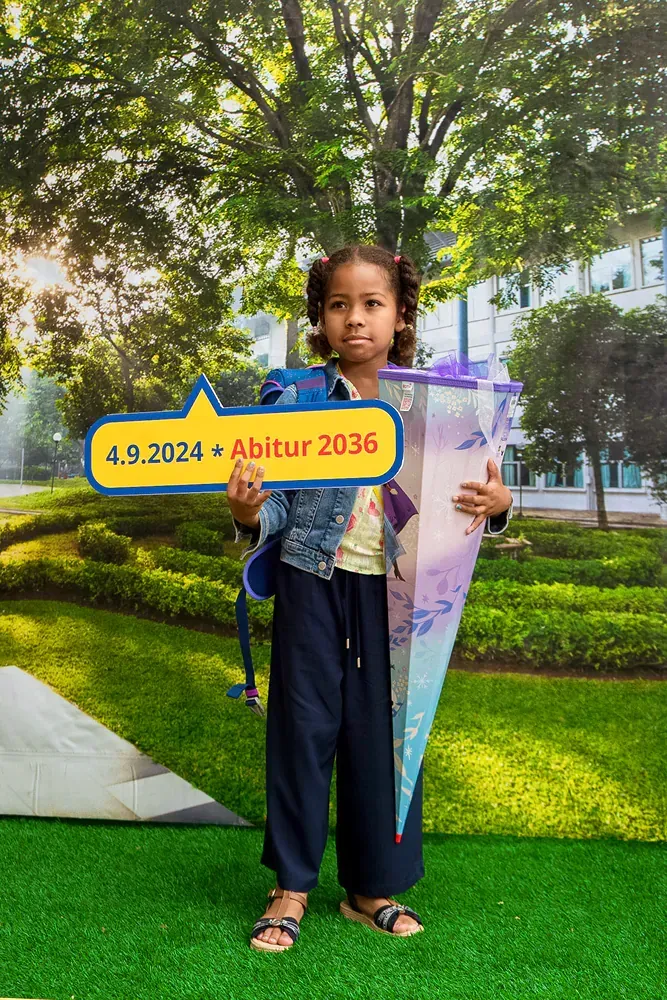 A little girl is holding a sign that says abitur 2036.
