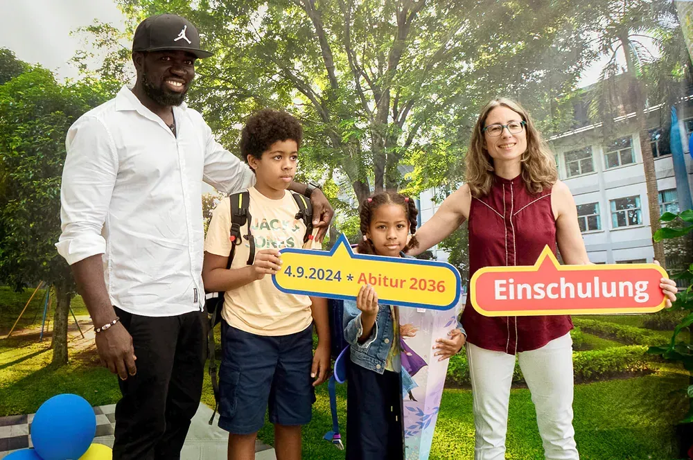 A family is posing for a picture while holding a sign that says einschulung.