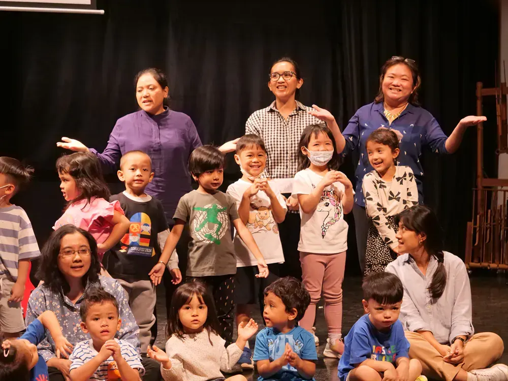A group of children and adults are posing for a picture on a stage.