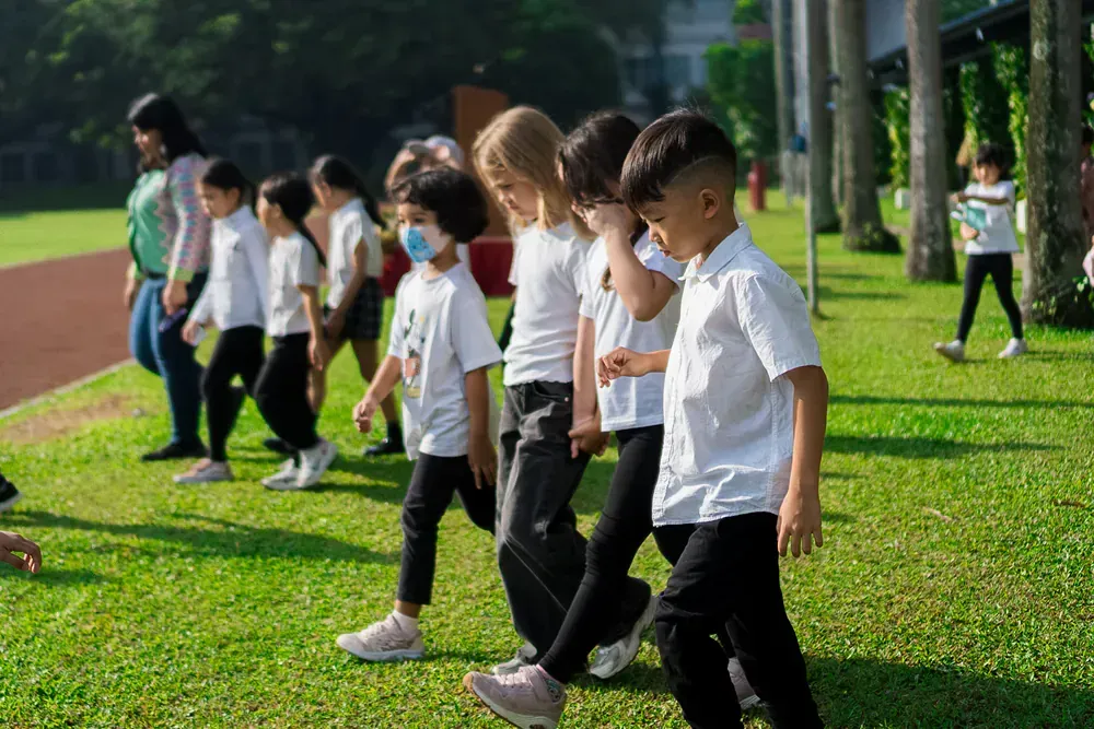 A group of children are walking on a lush green field.