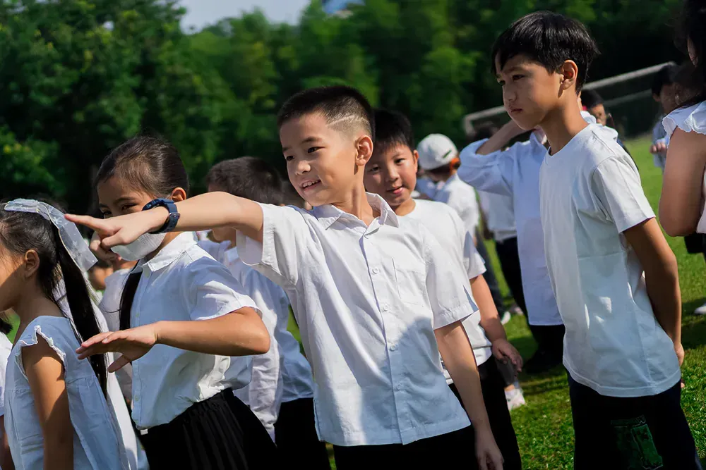 A group of children are standing in a line on a field.