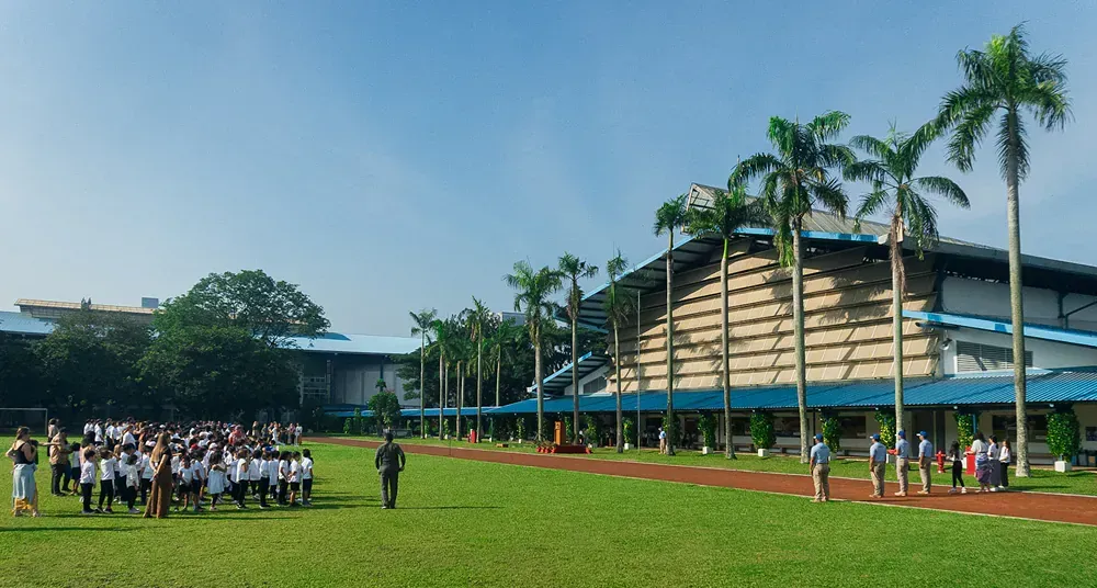 A group of people are standing in a field in front of a large building.