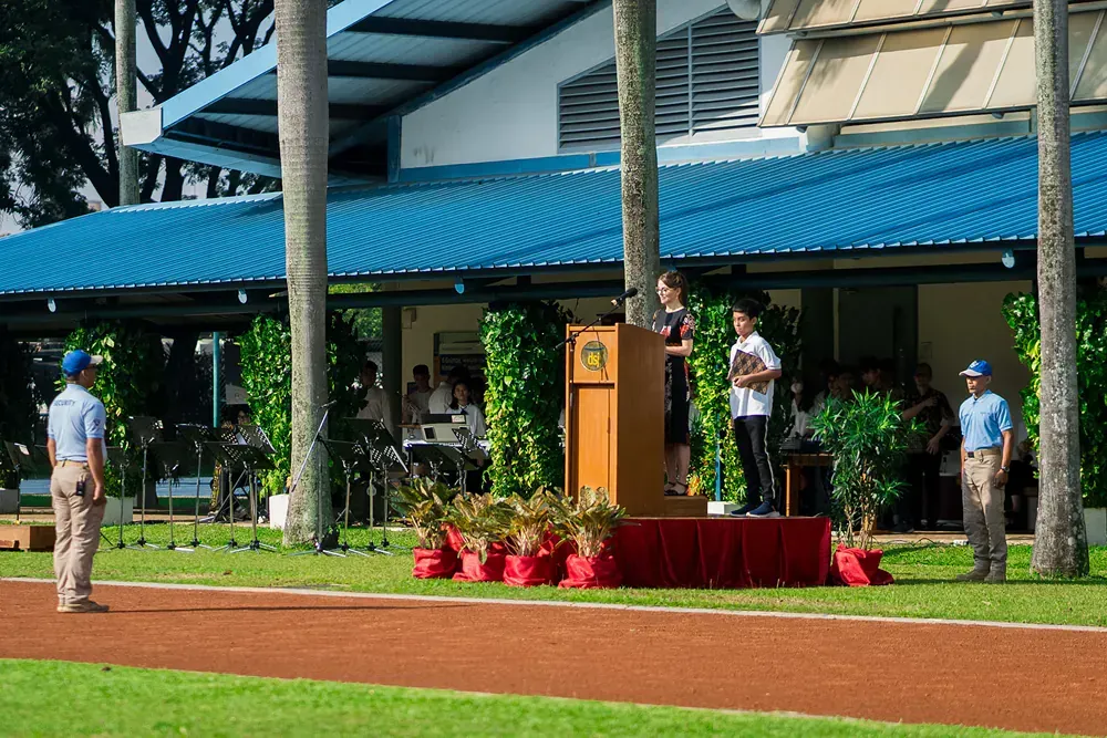 A woman is giving a speech at a podium in front of a building.