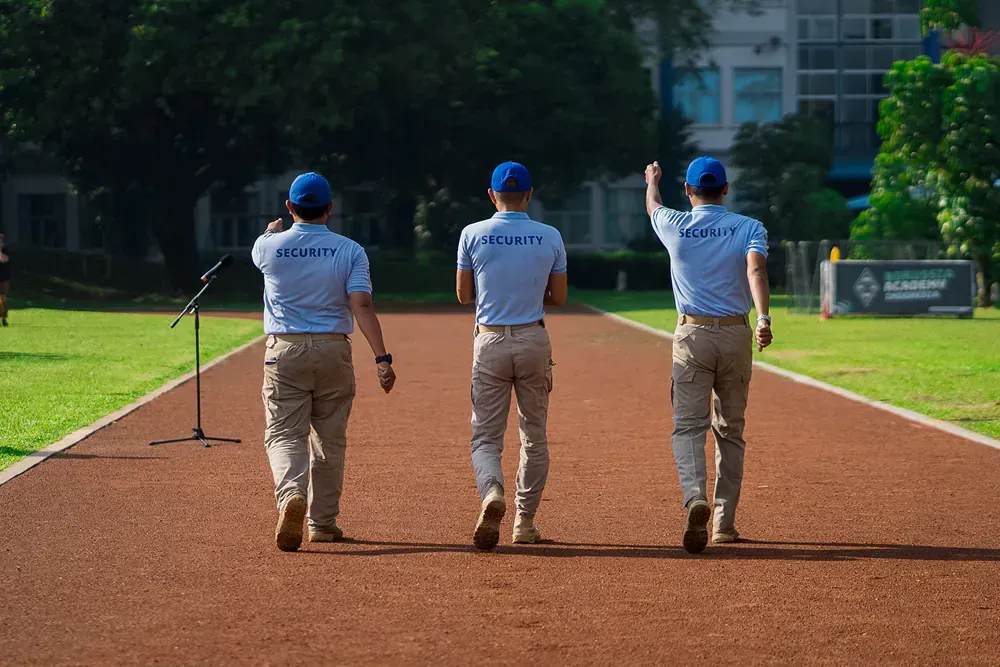 Three men are walking down a track in front of a microphone.