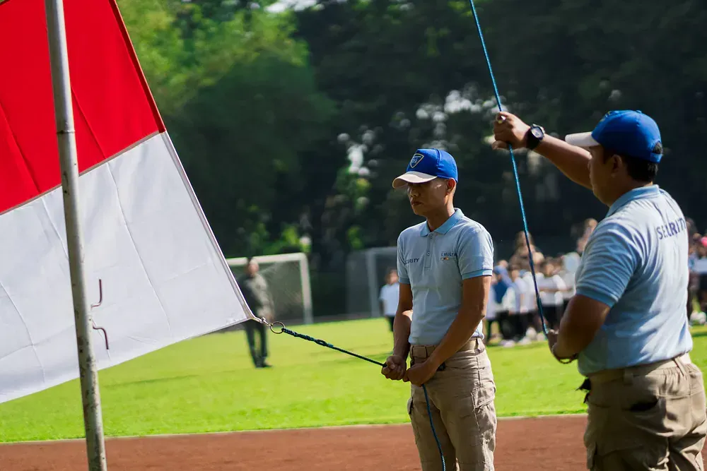 Two men are standing next to each other on a field holding a flag.