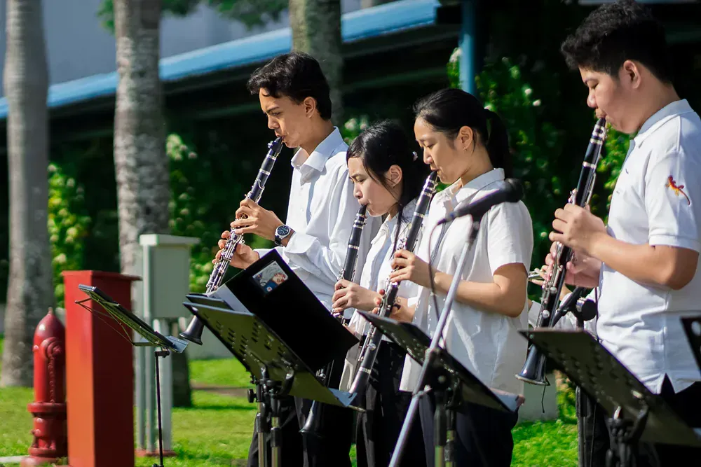 A group of people are playing clarinets in a park.