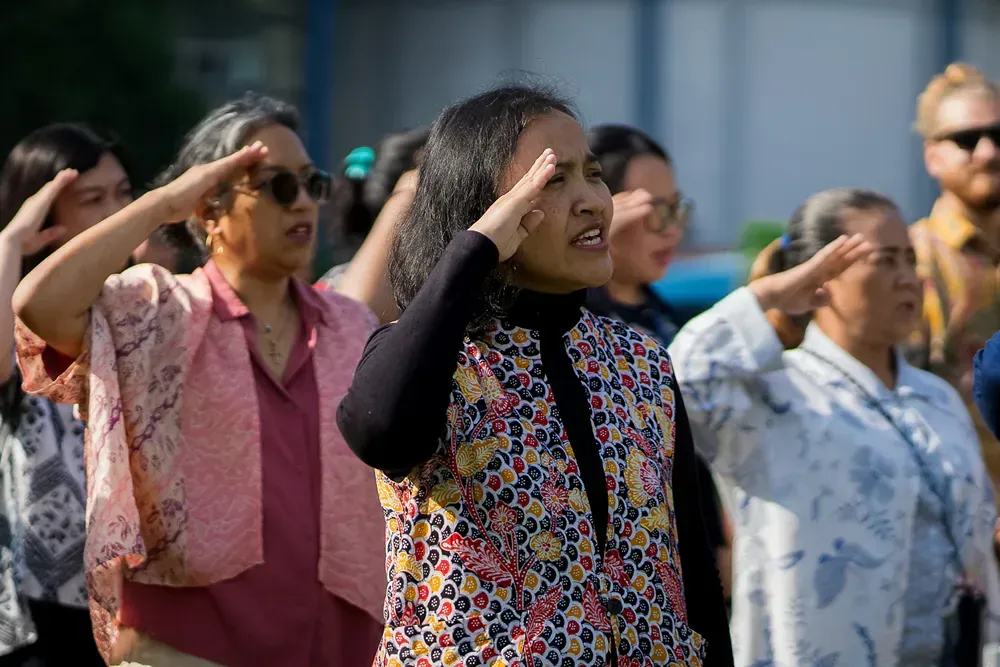 A group of people are saluting in a line.