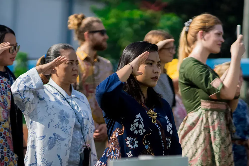 A group of people are standing in a line saluting.