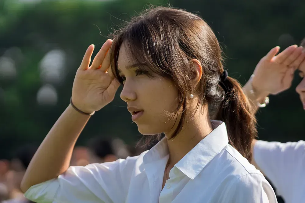 A woman in a white shirt is saluting in front of a crowd.