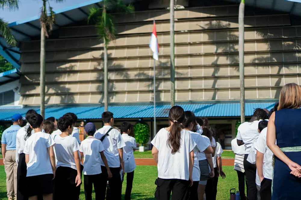 A group of people are standing in front of a flag pole.