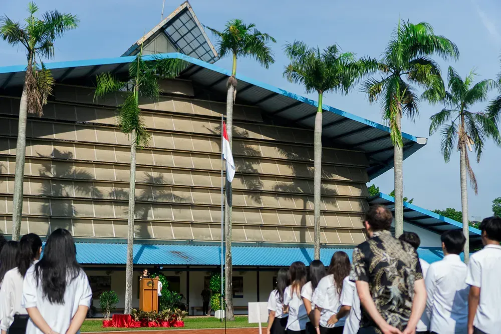 A group of people standing in front of a building with palm trees.