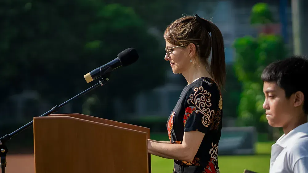 A woman is giving a speech at a podium next to a boy.