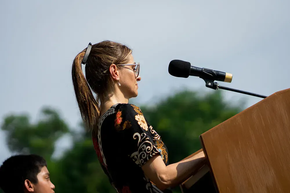 A woman is standing at a podium speaking into a microphone.