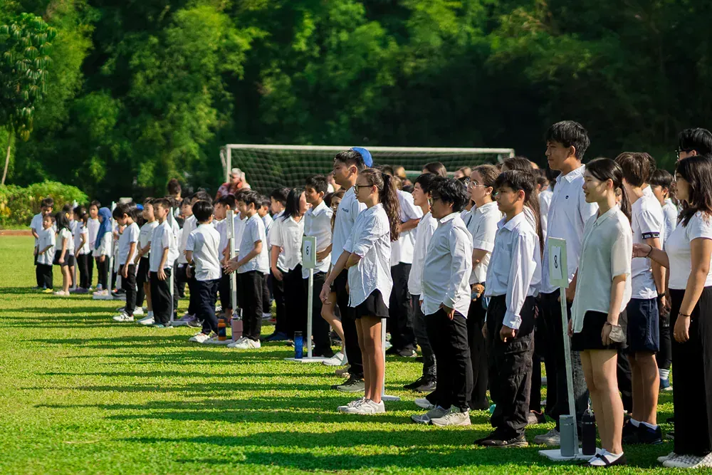 A large group of students are standing in a line on a soccer field.