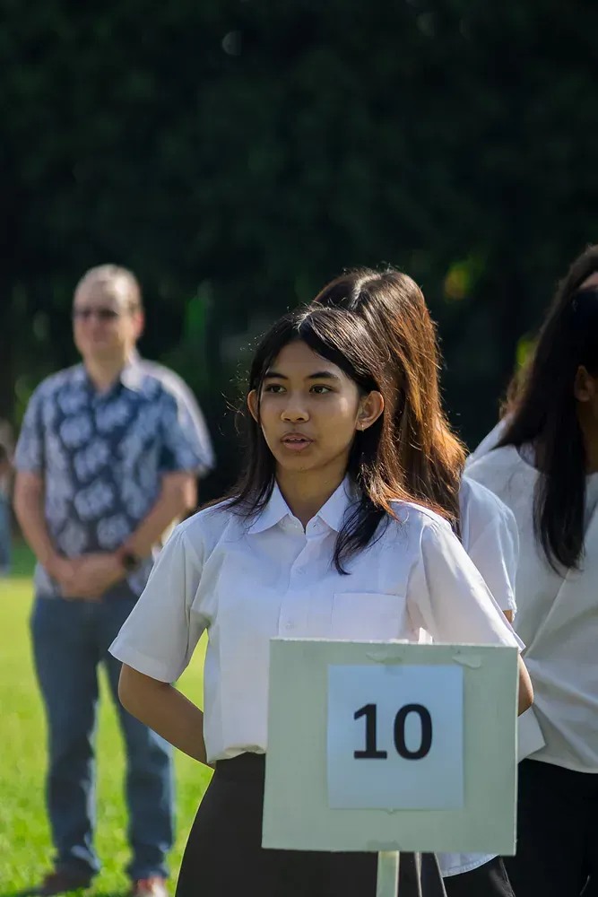 A girl is holding a sign with the number 10 on it.