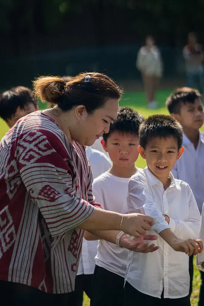 A woman is teaching a group of children how to wash their hands.