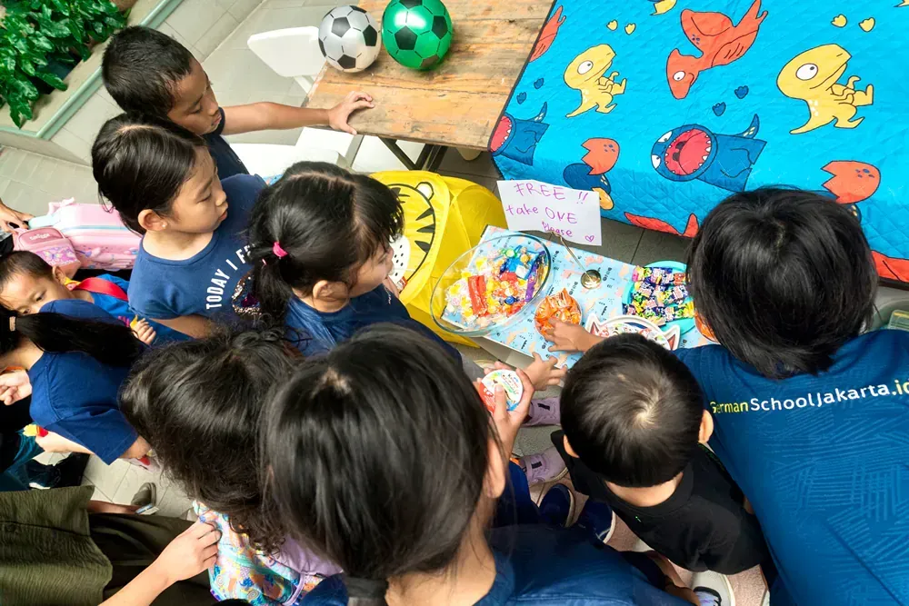 A group of children are sitting around a table playing with toys.