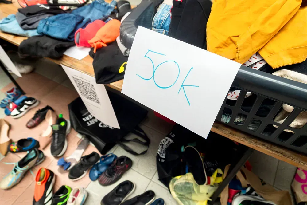 A table full of shoes and clothes with a sign that says 50k
