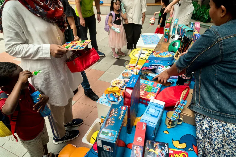 A group of people are standing around a table filled with toys.