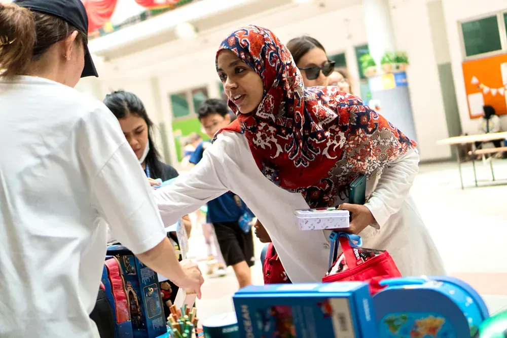 A woman in a hijab is shaking hands with a child.