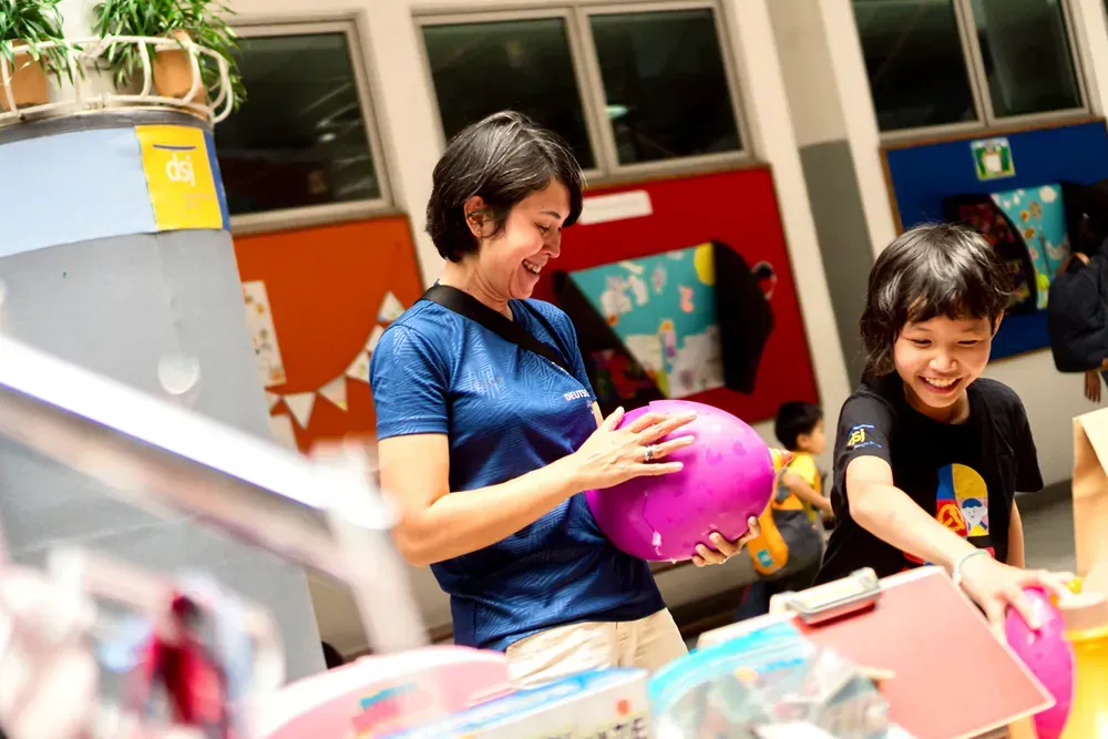A woman and a child are playing with balloons in a room.