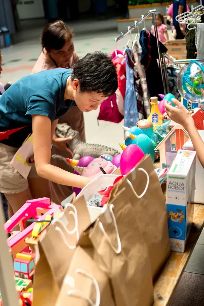 A woman is standing in front of a table full of toys.