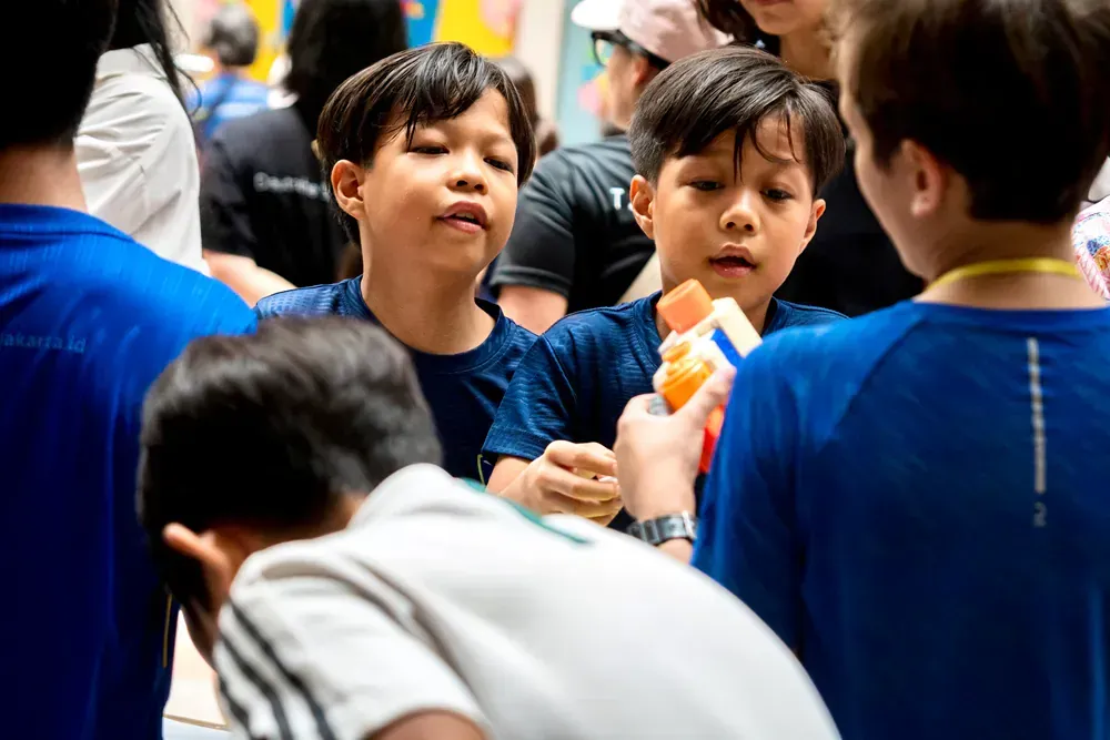 A group of young boys are playing with a toy in a crowd of people.