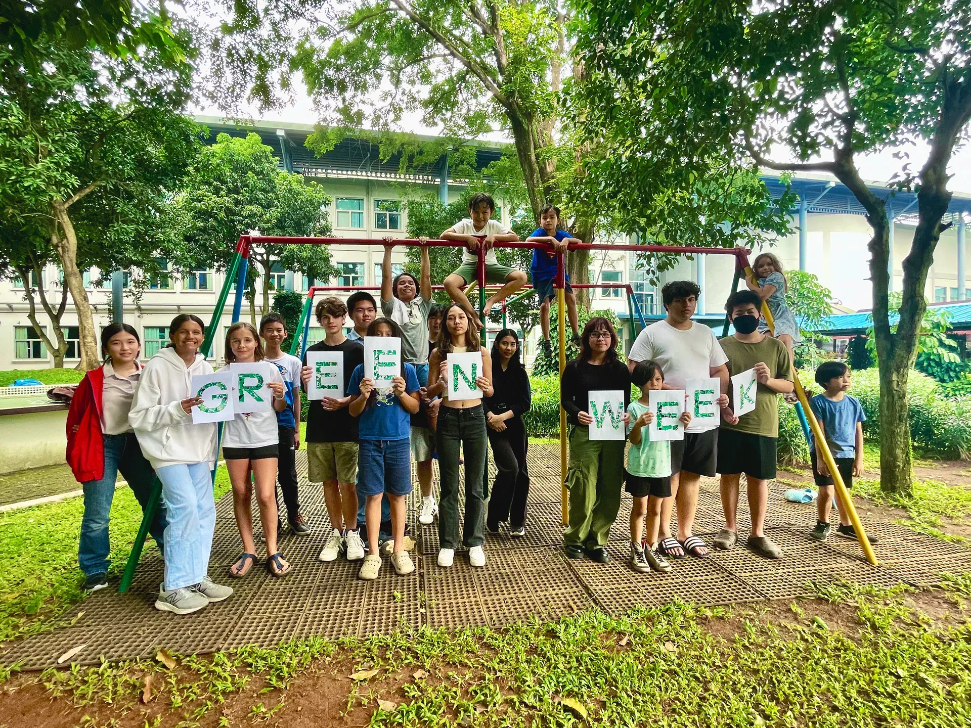 Students are standing next to each other at DSJ park holding signs that say ''green''