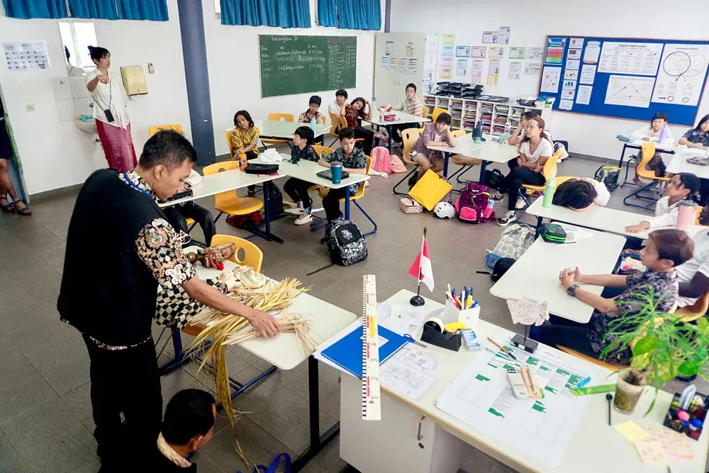 A man is standing in front of a classroom full of children.