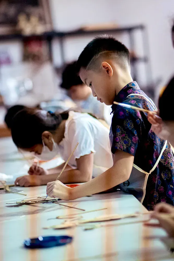 A group of children are sitting at a table painting.