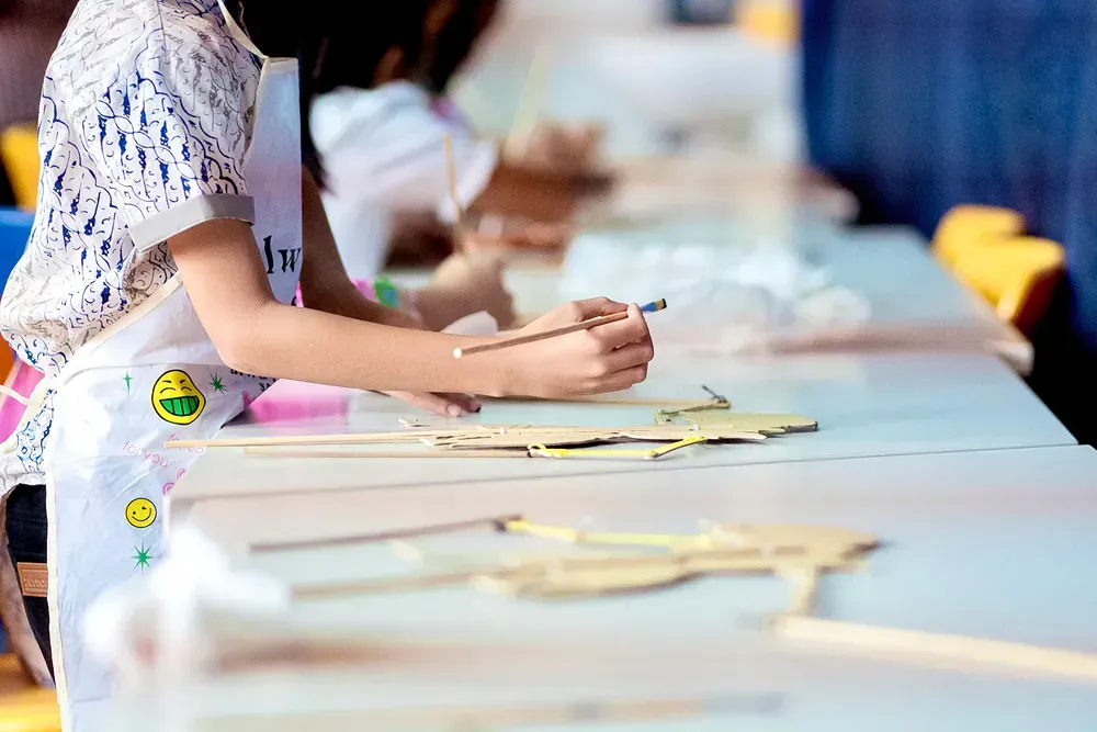 A little girl is sitting at a table with a pencil in her hand.