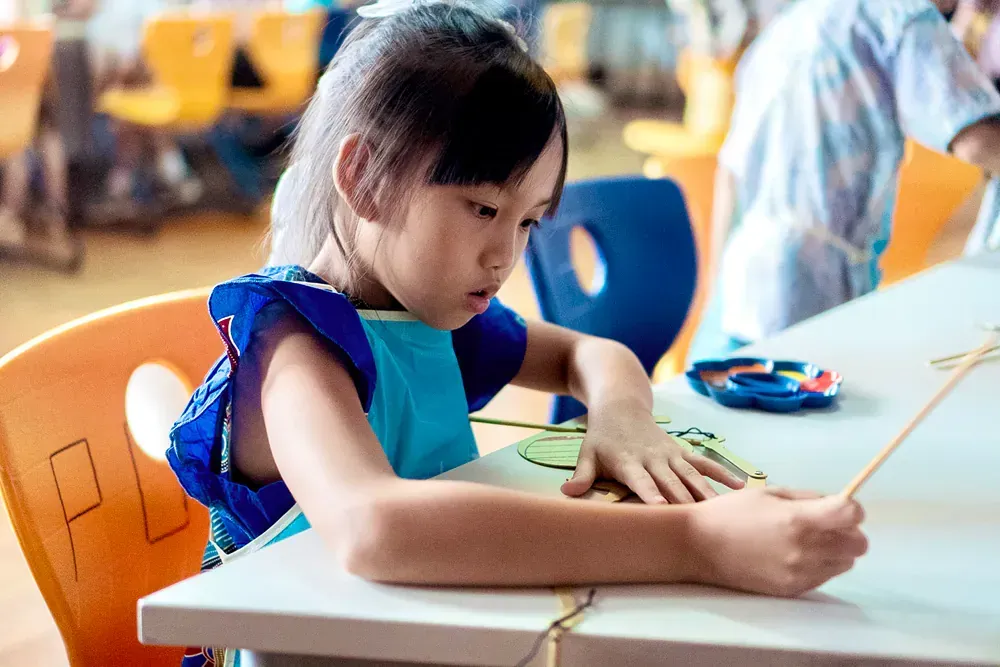 A little girl is sitting at a table in a classroom.