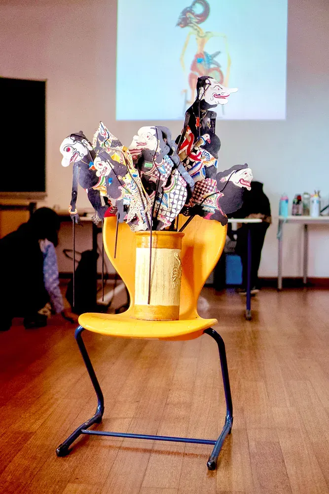 A yellow chair with a vase on top of it in a classroom.