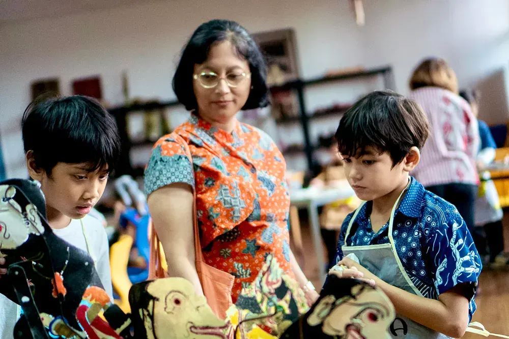 A woman is standing next to two young boys in a room.