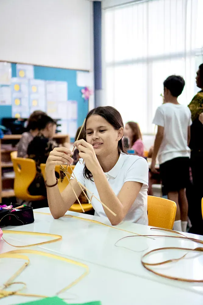 A young girl is sitting at a table in a classroom playing with a toy.