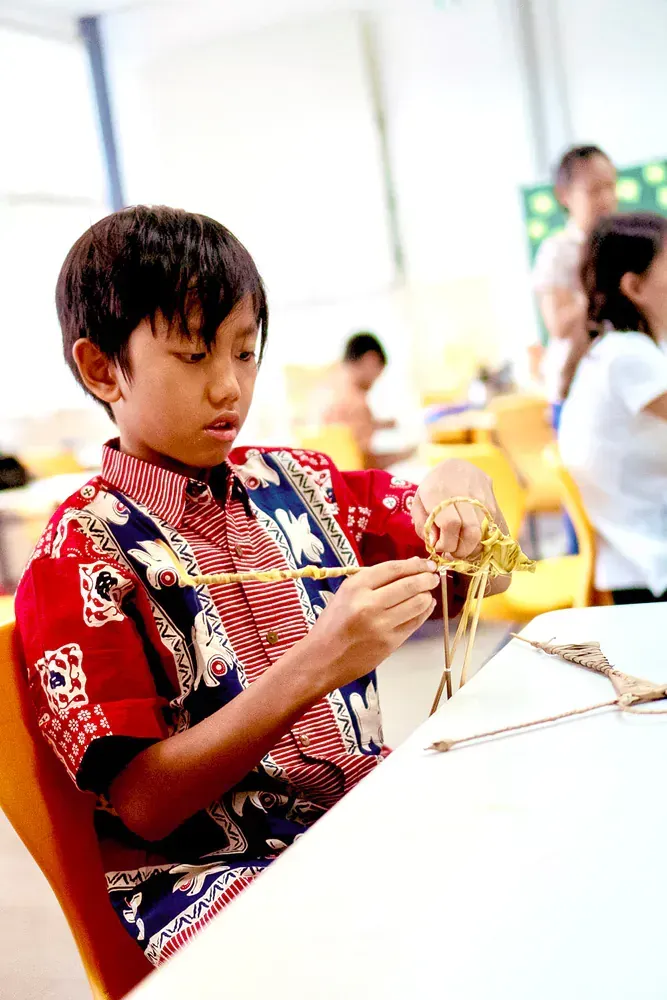 A young boy is sitting at a table with scissors in his hands.