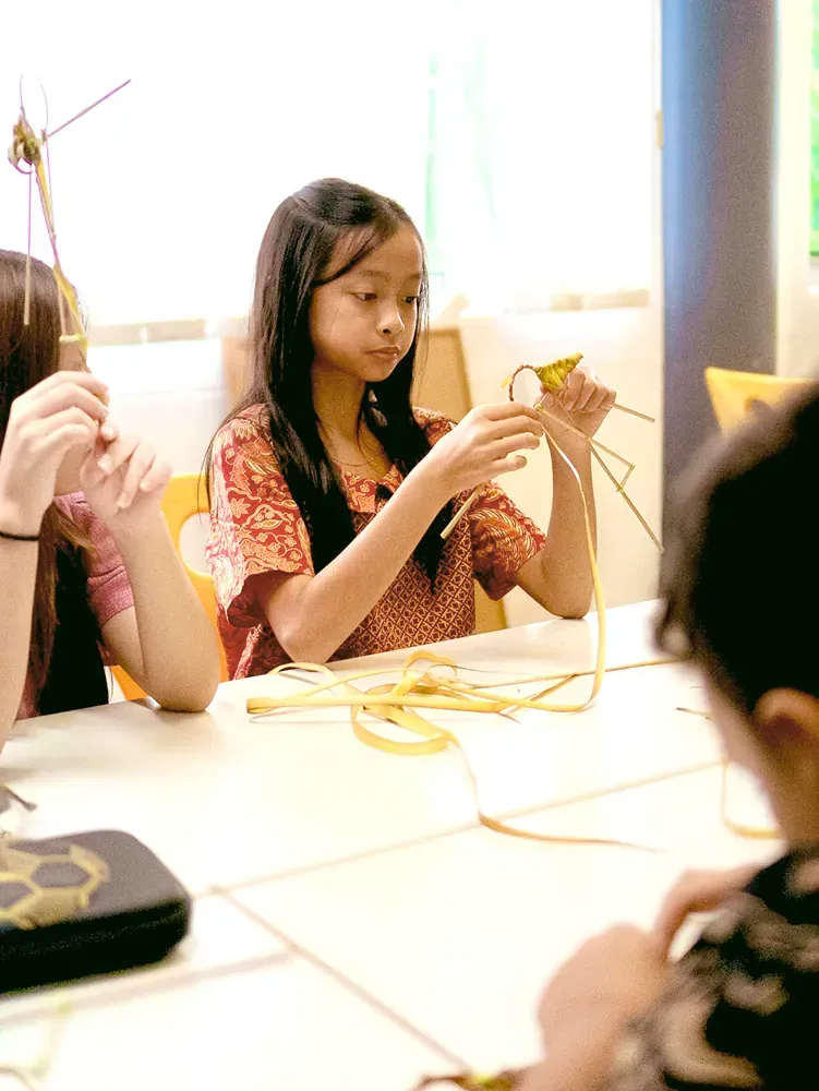 A group of children are sitting at a table making crafts.